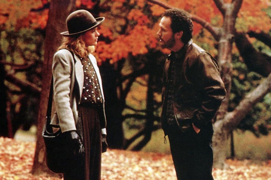 man and woman talking to each other with fall colored trees in the background