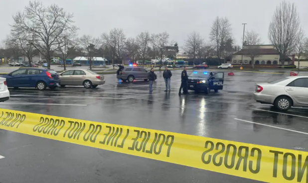 picture of Lakewood parking lot with crime scene tape, police officers, and others.