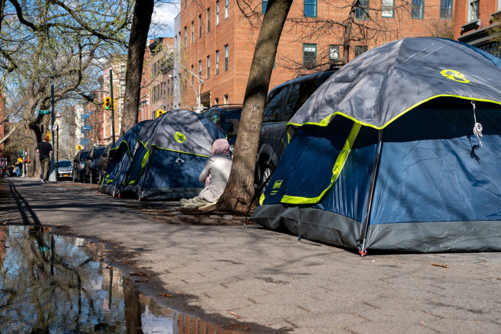 A person seats between tents belonging to homeless people who were removed from an encampment on East 9th Street earlier this week and have relocated a block adjacent to Tompkins Square Park in Manhattan in New York City, U.S., April 8, 2022.  REUTERS/David Dee Delgado